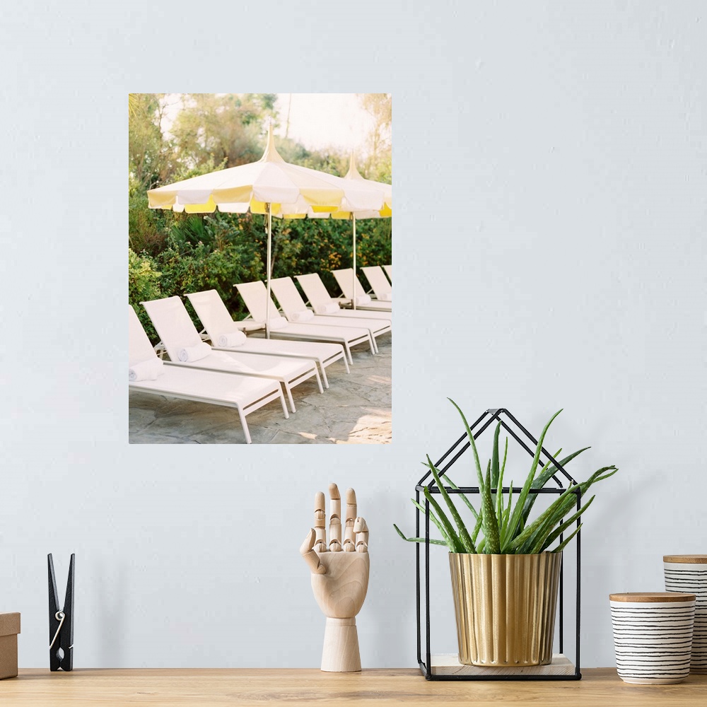 A bohemian room featuring A photograph of a neat row of pool loungers with rolled towels underneath yellow umbrellas.