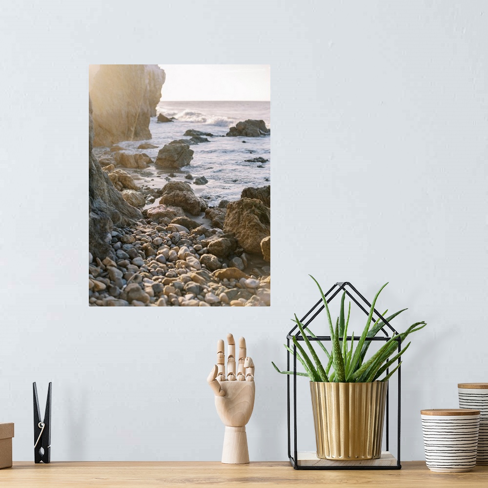 A bohemian room featuring A photograph of rocks and boulders at the edge of a rugged coastline at sunset.
