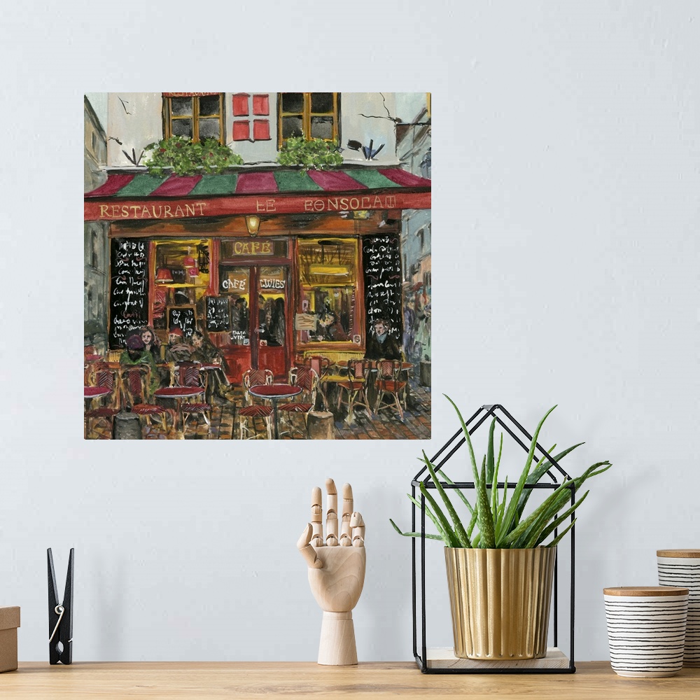 A bohemian room featuring A square decorative image of people sitting outside a red and green cafe in France.