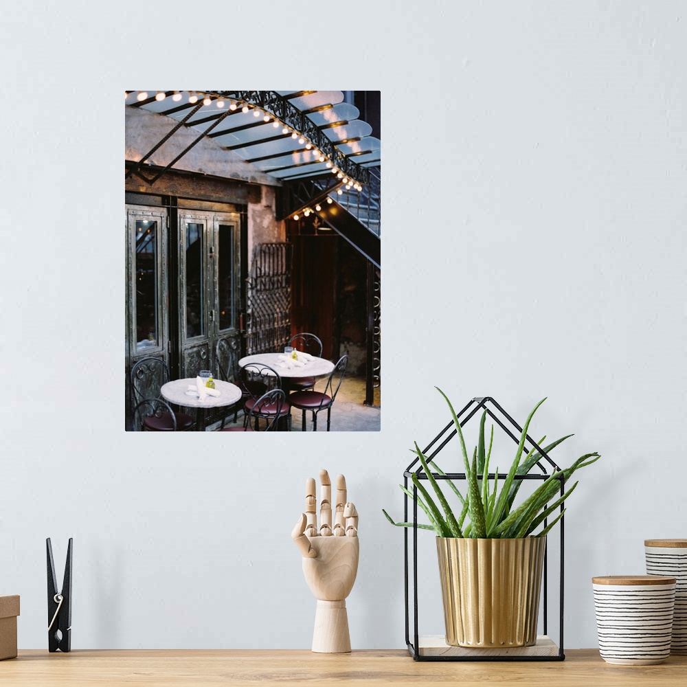 A bohemian room featuring A photograph of the tables and lights of a rustic mediterranean cafe.