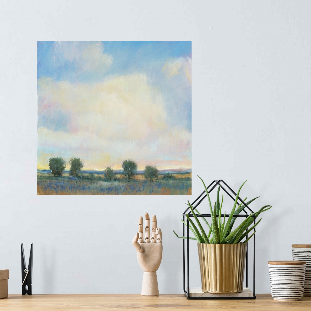 A bohemian room featuring Abstracted landscape painting with a field and trees below a cloudy, blue sky.