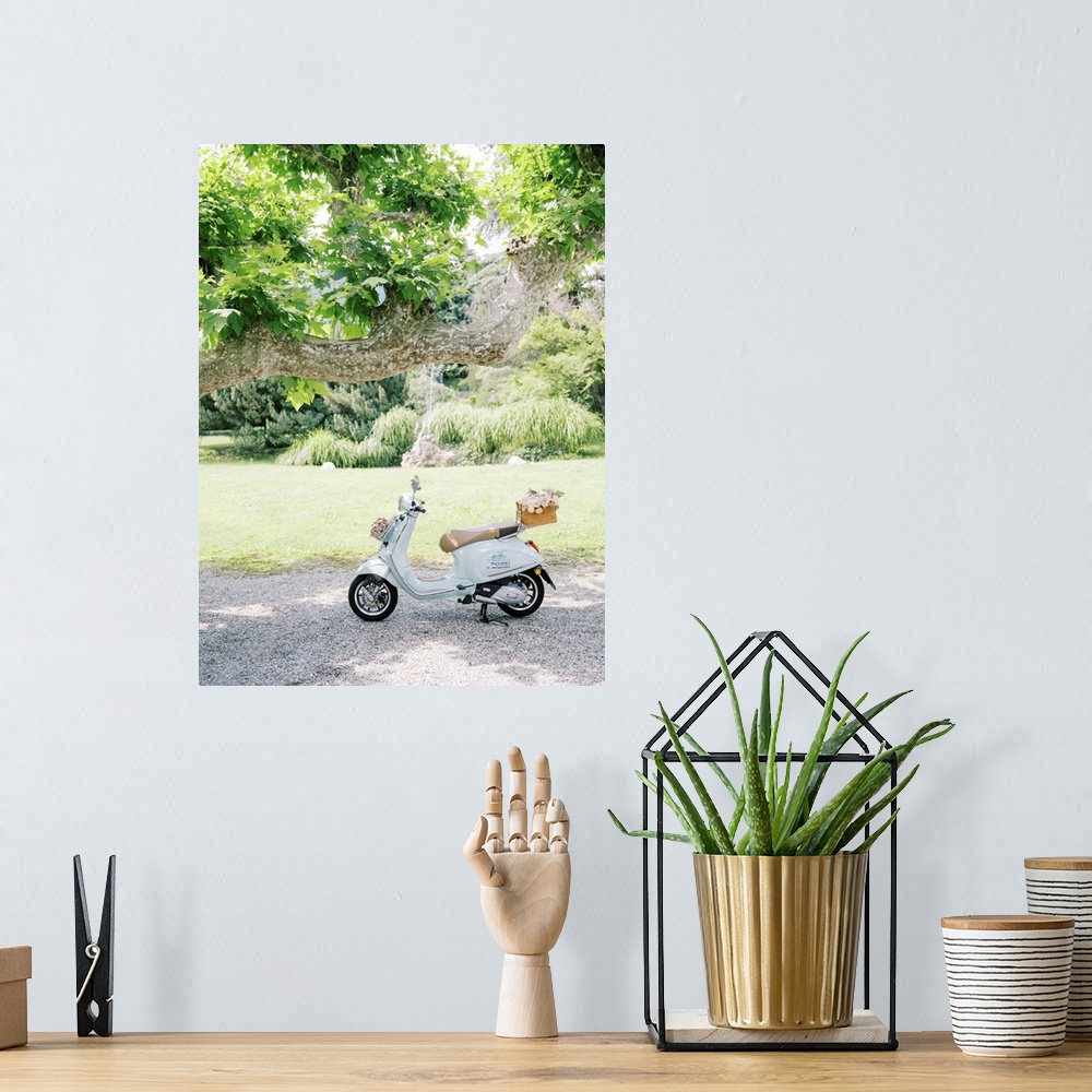 A bohemian room featuring A photograph of a pale blue motor scooter with a basket of flowers on the back parked underneath ...