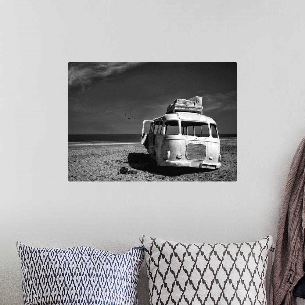 A bohemian room featuring Black and white image of an abandoned bus with windows missing on a sandy beach in Belgium.