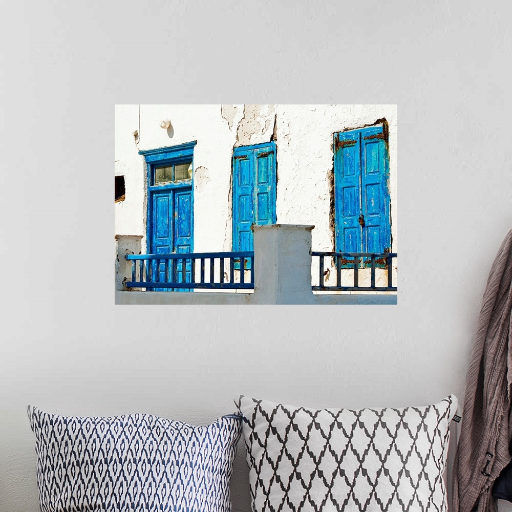 A bohemian room featuring Photograph of brightly-painted distressed doors against a stark, white wall on the Cycalades Isla...