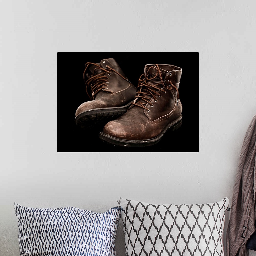 A bohemian room featuring A pair of well-worn brown boots with laces.
