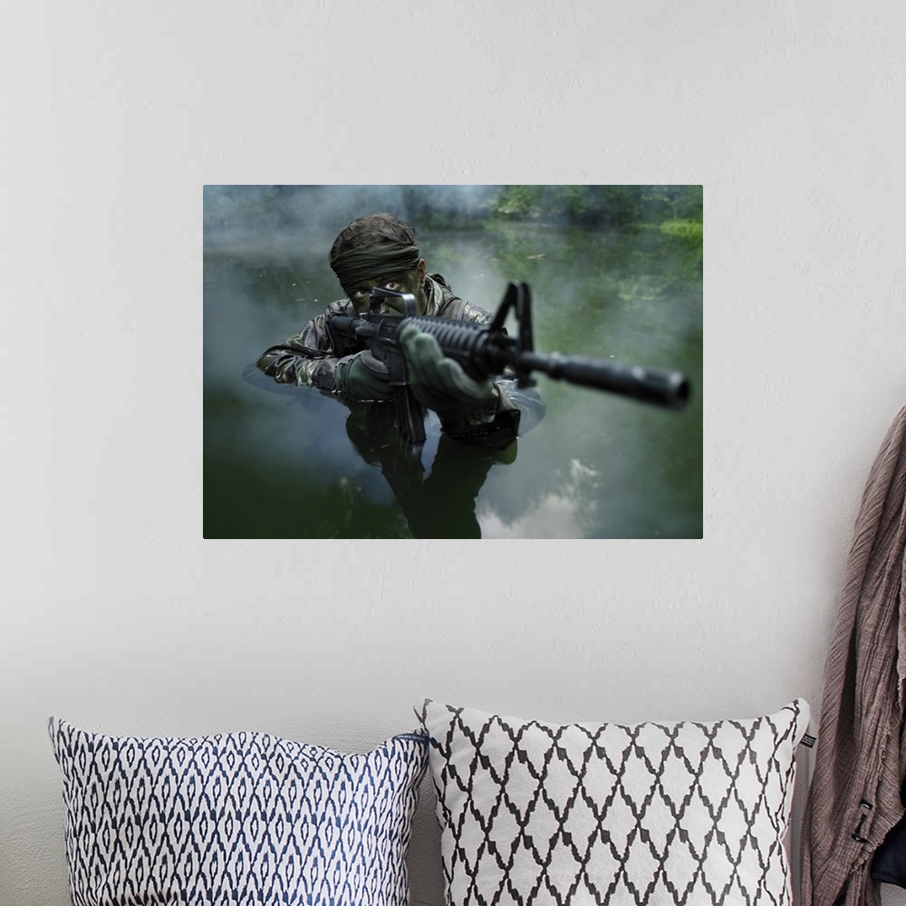 A bohemian room featuring Special operations forces soldier transits the water armed with an assault rifle.