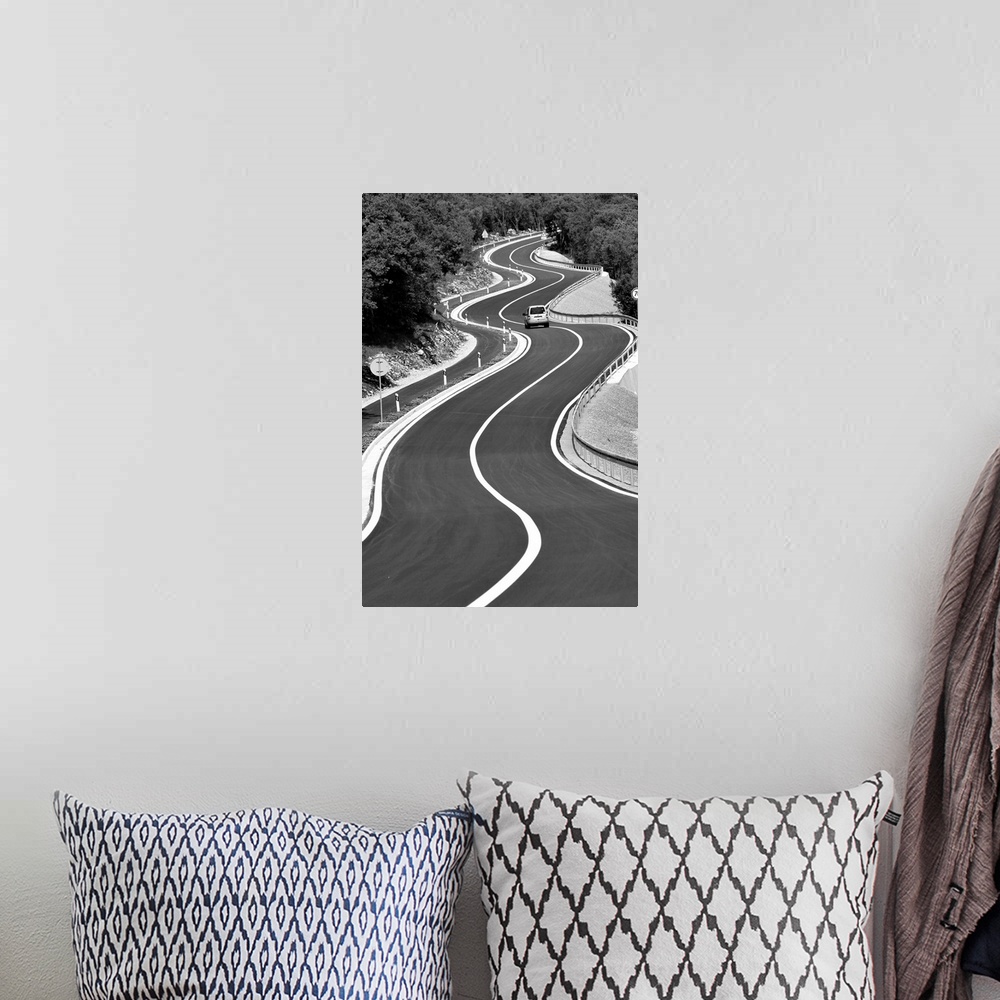 A bohemian room featuring A car traveling down a stretch of very curvy road.