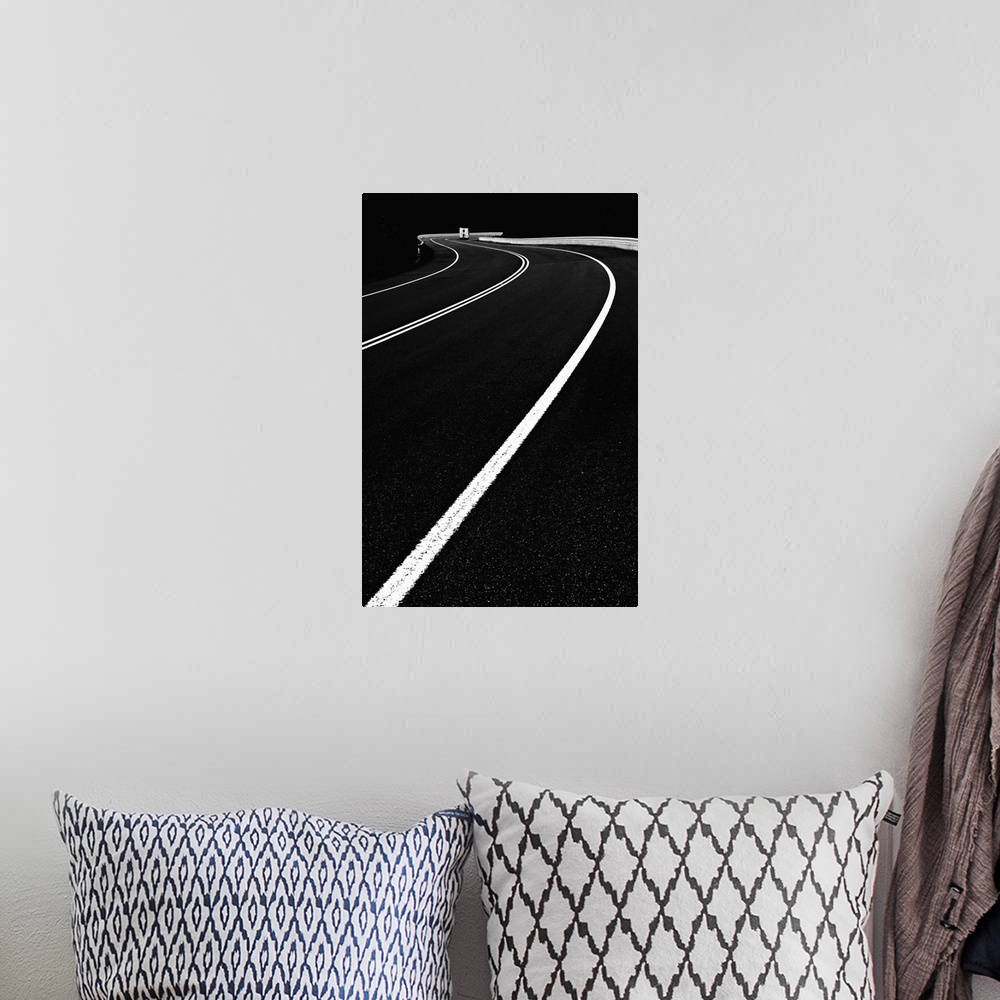 A bohemian room featuring High contrast black and white image of lines on a road curving around a bend.