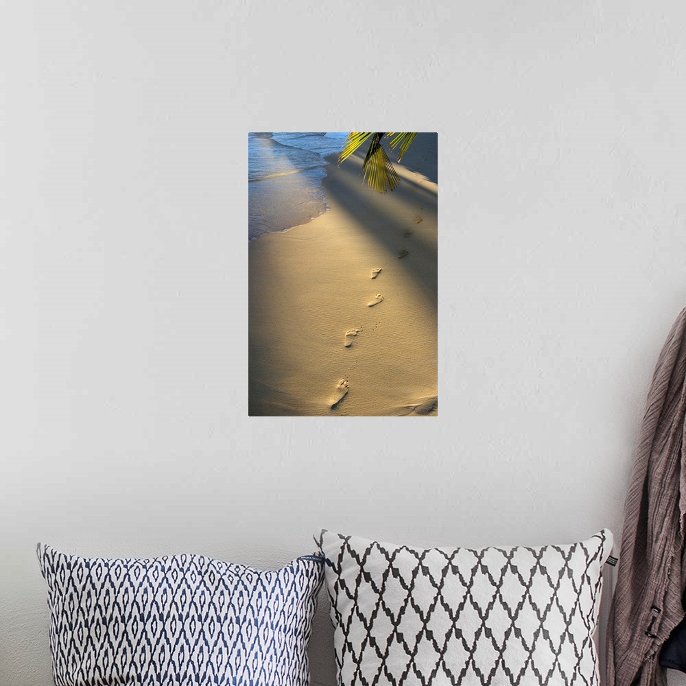 A bohemian room featuring Vertical photograph on a large wall hanging of a single row of footprints in the sand, near the s...