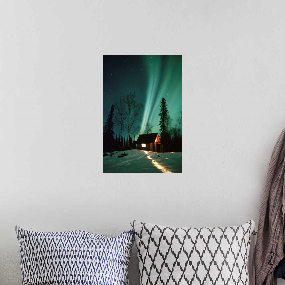 A bohemian room featuring A photograph of the Aurora Borealis wisps in starry sky above a small cabin in the snow.