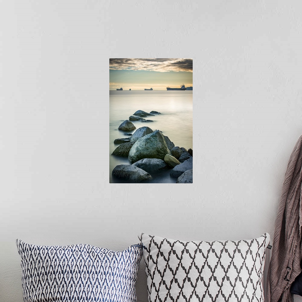 A bohemian room featuring Ships out in the Pacific ocean off the coast of Stanley Park with rocks in the foreground; Vancou...