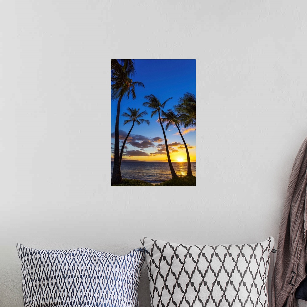 A bohemian room featuring The sun setting through silhouetted palm trees; Wailea, Maui, Hawaii, United States of America