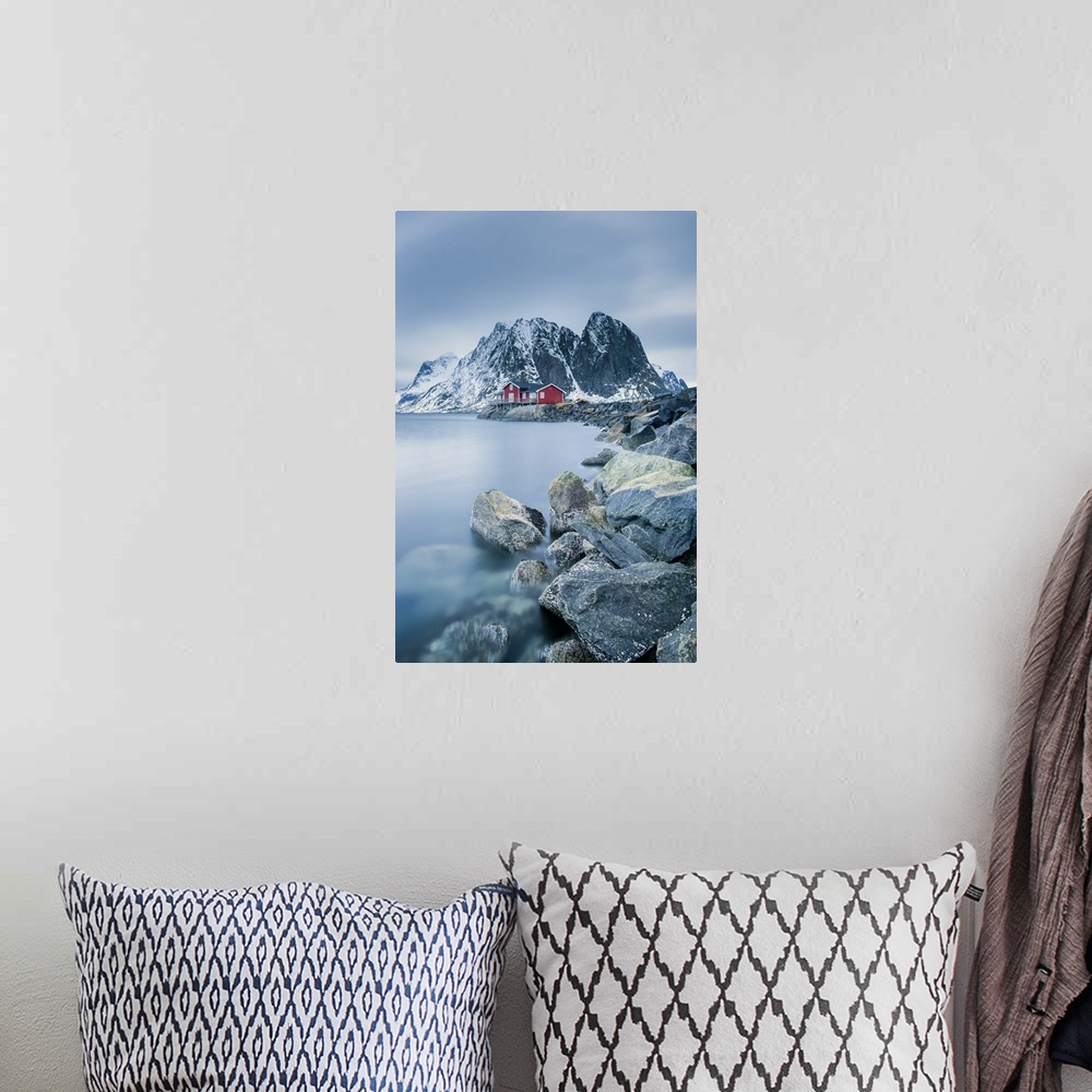 A bohemian room featuring A photograph of a Norwegian red cabin with gray mountain boulders all around.
