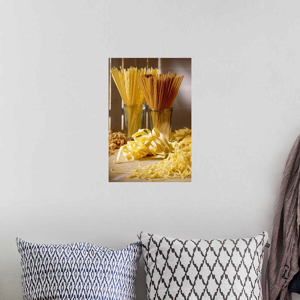 A bohemian room featuring Dry pasta in glass jars and fresh pasta scattered in front of it is photographed artistically.