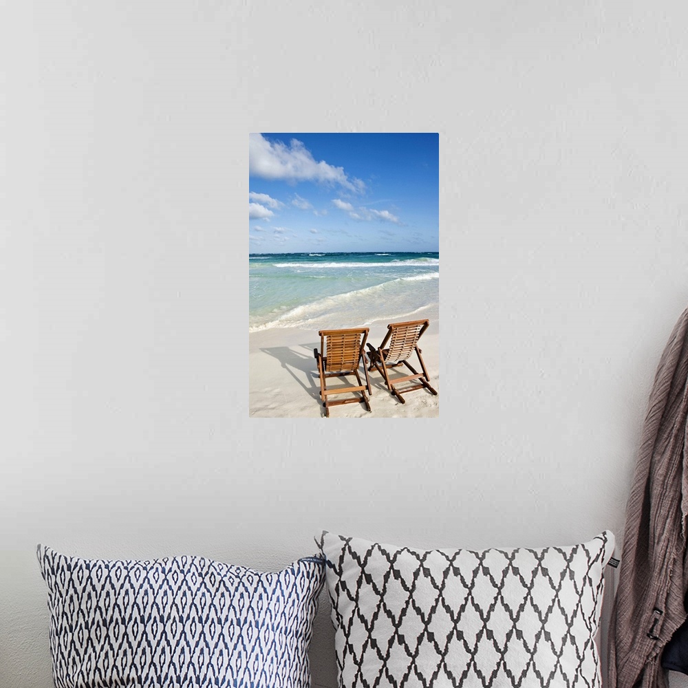 A bohemian room featuring Portrait photograph on a large wall hanging of two wooden lounge chairs on the beach, facing clea...
