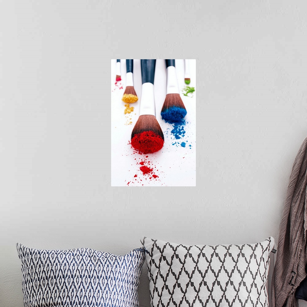 A bohemian room featuring A vertical photo of makeup brushes heavily filled with pigment resting on blank a surface.