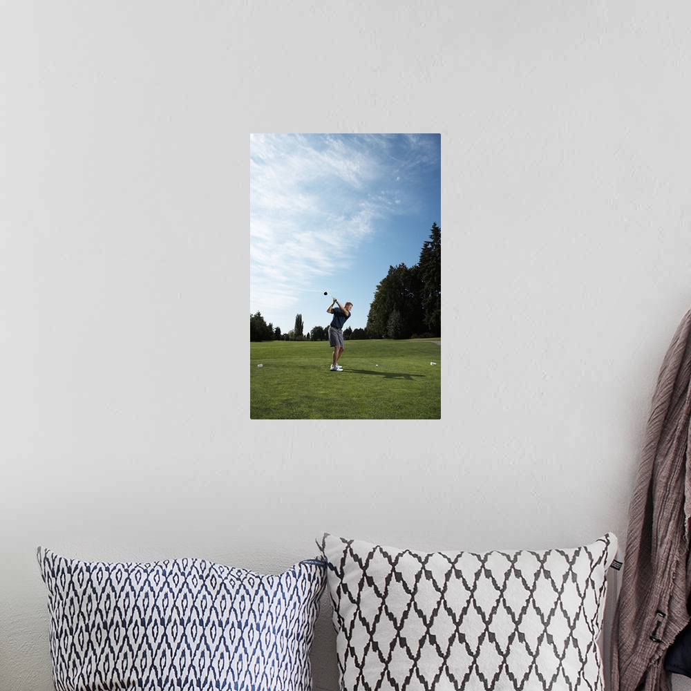 A bohemian room featuring Golfer swinging club on golf green, side view