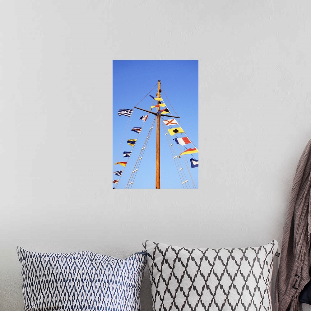 A bohemian room featuring Multiple flags on the mast of a sailboat against a blue sky.