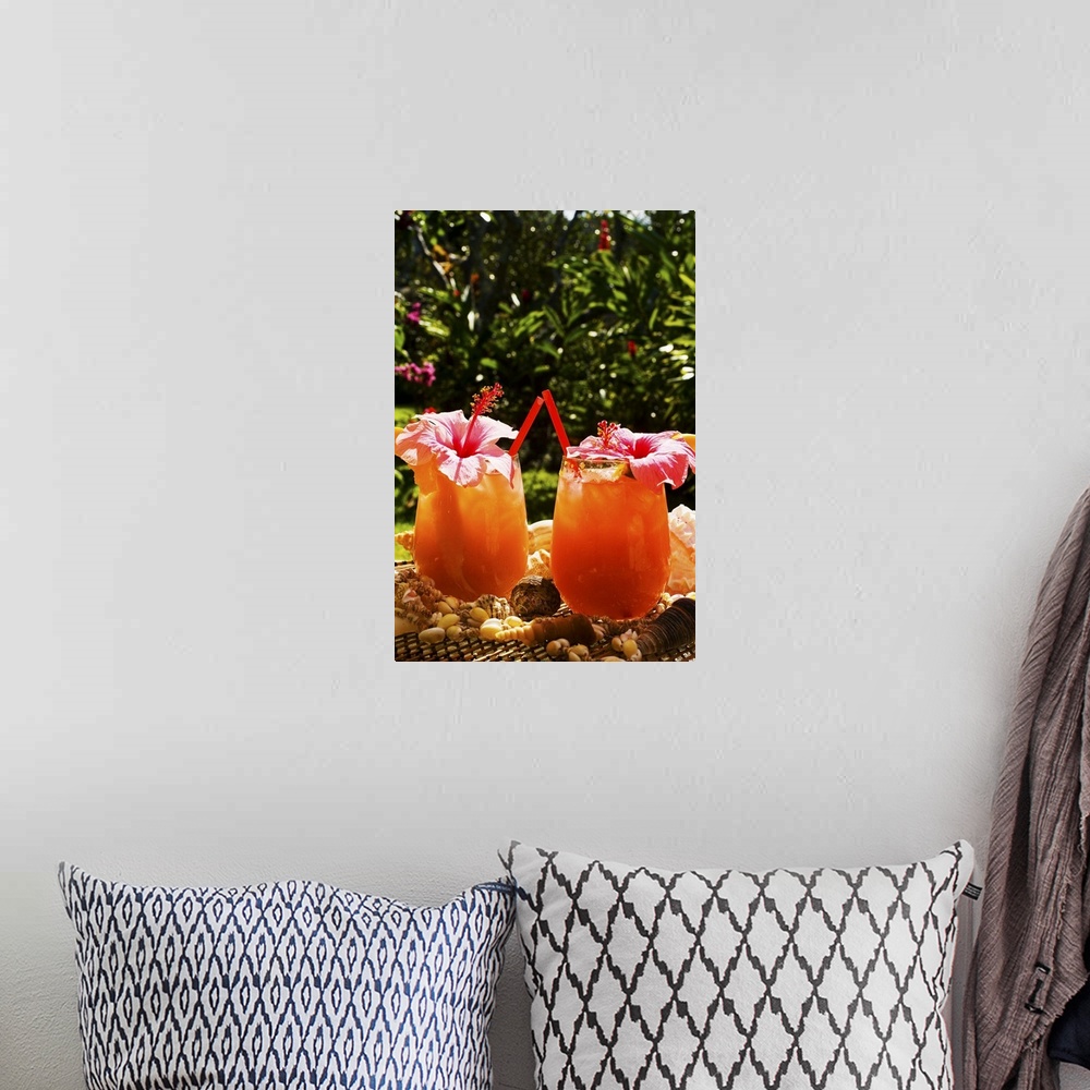 A bohemian room featuring Two tropical drinks garnished with flowers in an outdoor setting.