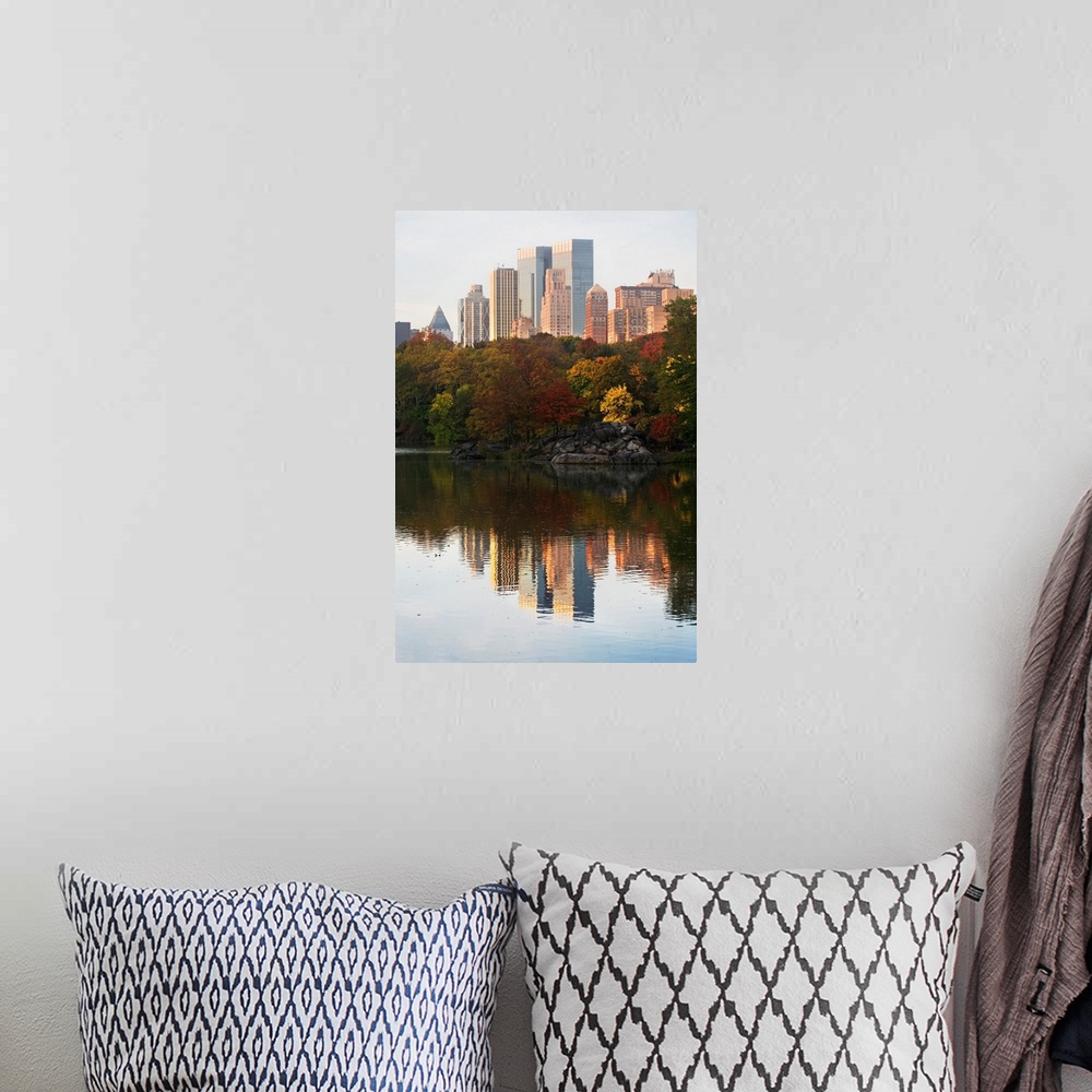 A bohemian room featuring This is a vertical photograph of autumn trees and skyscrapers reflecting in the calm waters of th...