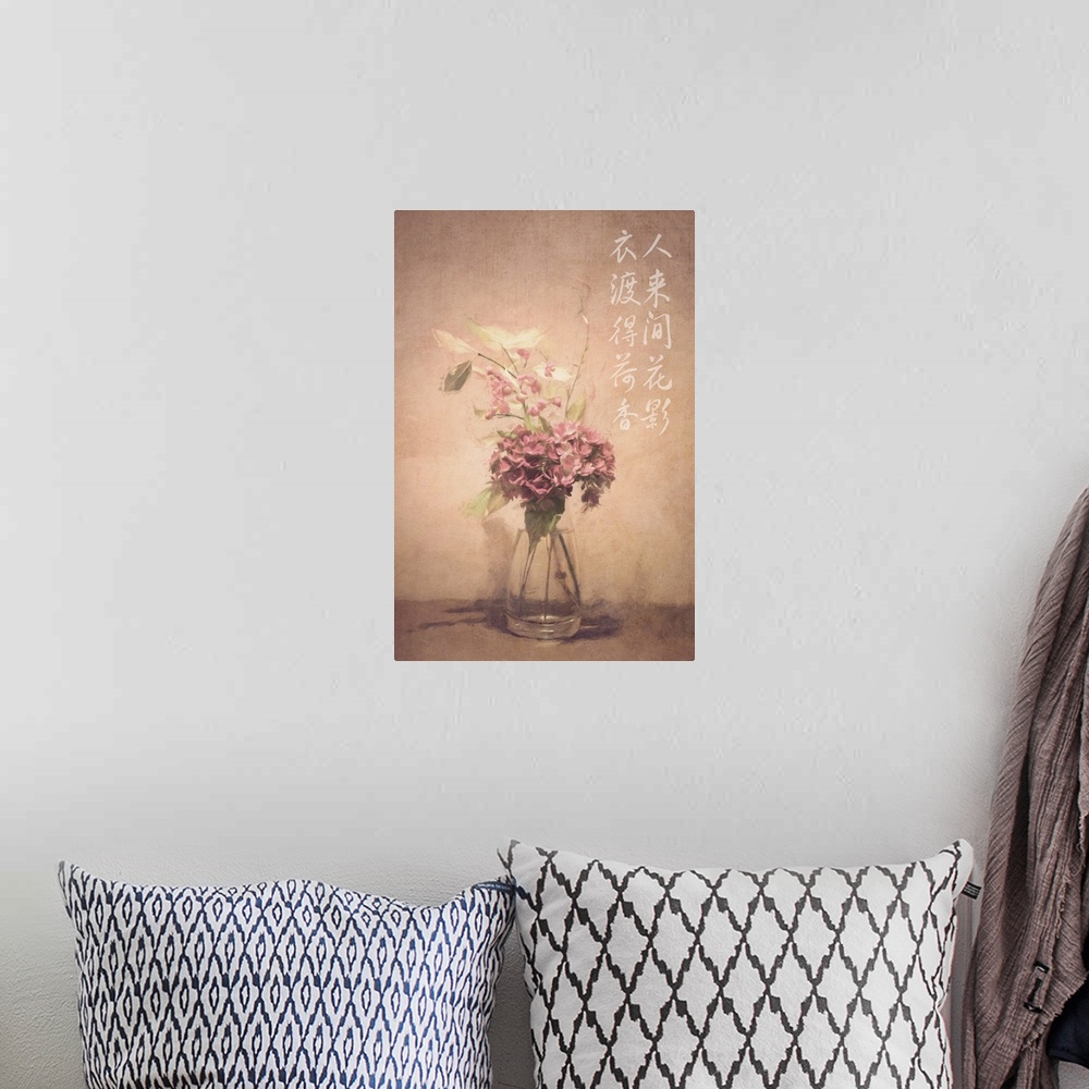 A bohemian room featuring Asian calligraphy on a wall beside dusty pink and white flowers in a clear glass vase.