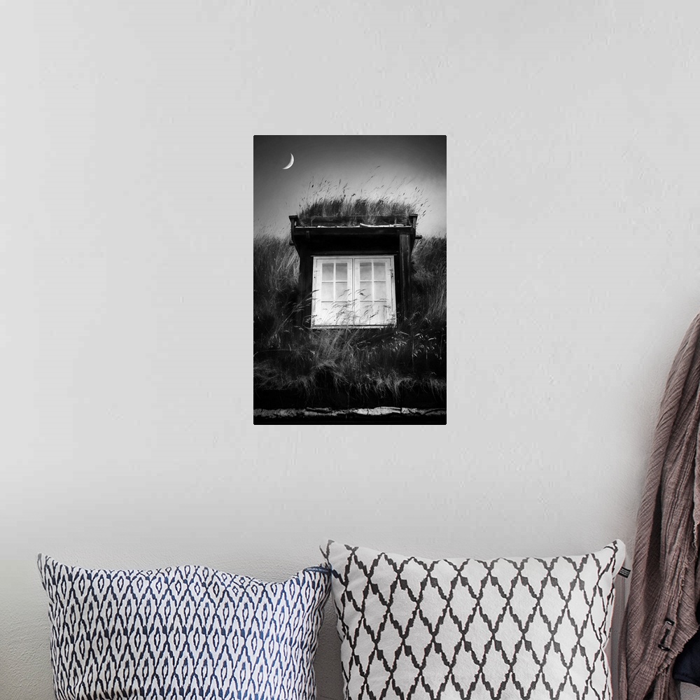 A bohemian room featuring Black and white image of a small structure with white windows and a crescent moon above.
