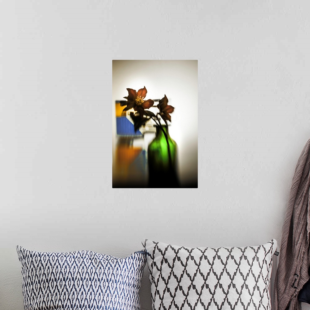A bohemian room featuring Distorted photograph of Christmas roses in a green glass jar.