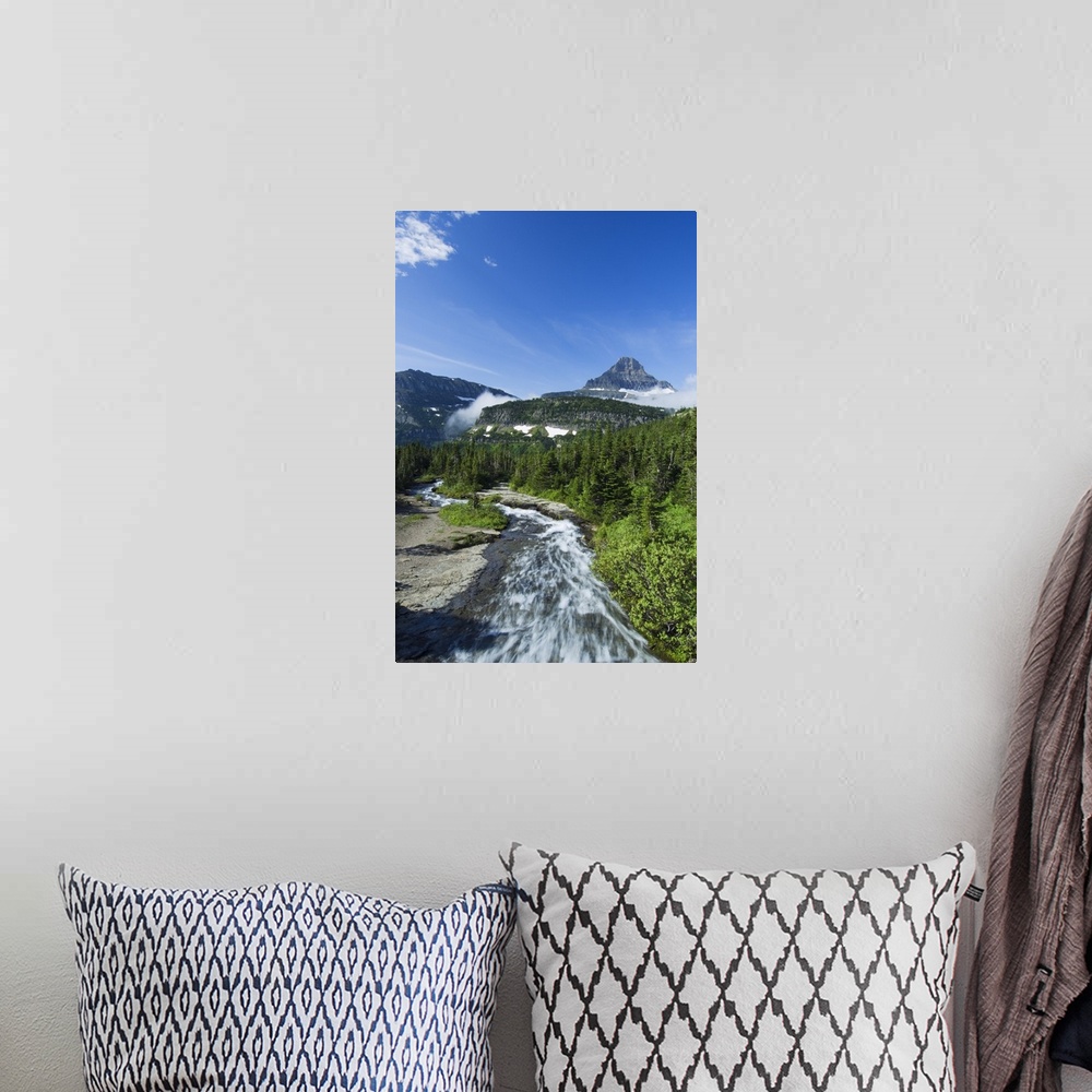 A bohemian room featuring High angle view of Siyeh Creek rushing through pine forest, distant Mount Reynolds against blue s...