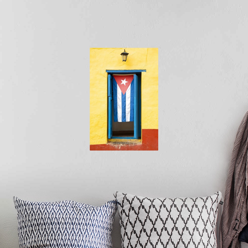 A bohemian room featuring Photograph of the Cuban flag hanging in a window on a yellow and red wall in Havana.
