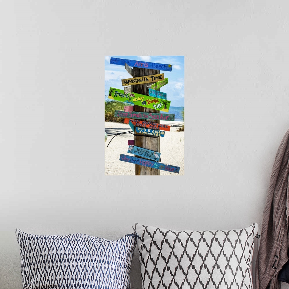 A bohemian room featuring A collection of colorful humorous signs on a wooden post on the beach.