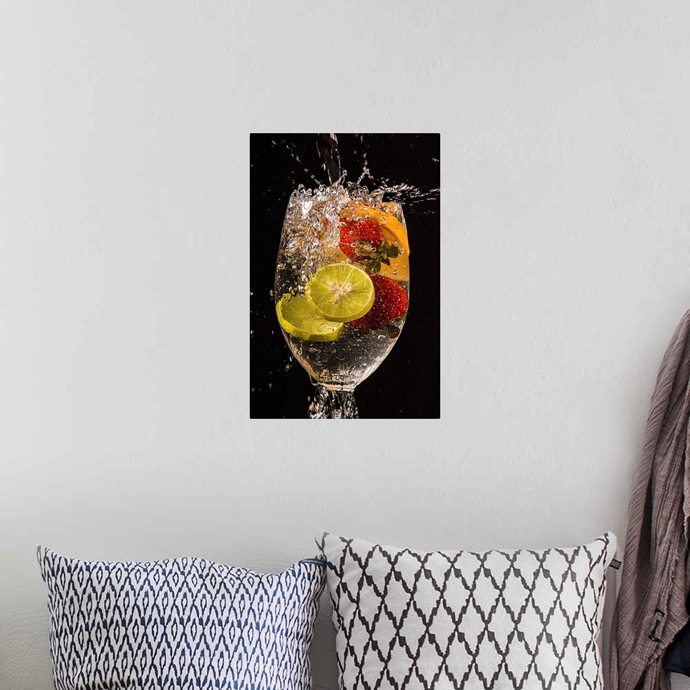 A bohemian room featuring Slices of lemons and oranges and whole strawberries splashing into a glass of water.