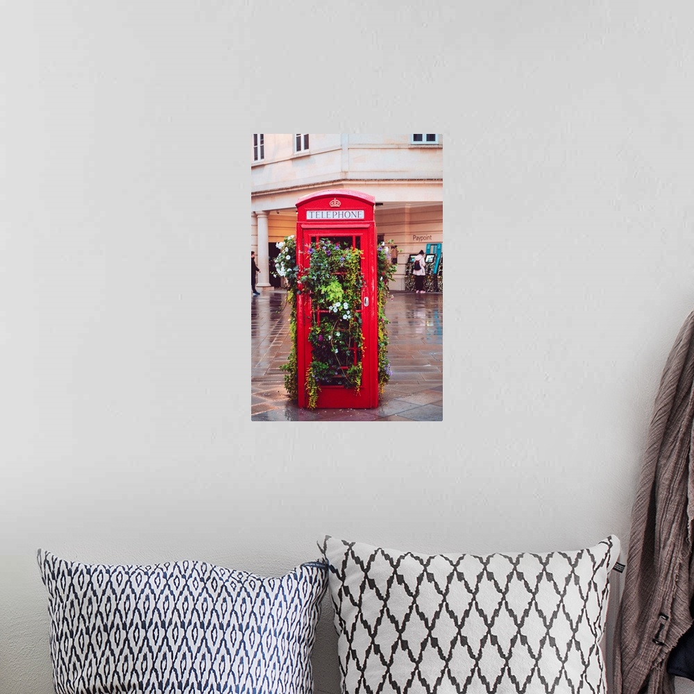 A bohemian room featuring A traditional British red telephone booth filled with plants in the city of Bath.