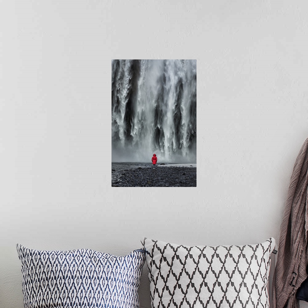 A bohemian room featuring Woman staring into Skogafoss waterfall in Iceland.