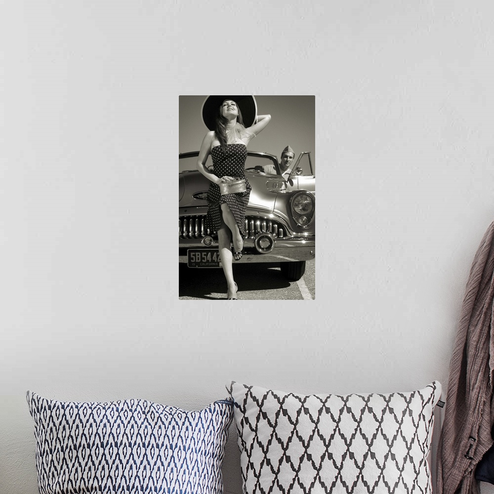 A bohemian room featuring A model wearing a large hat and a spotted dress with a 50's car