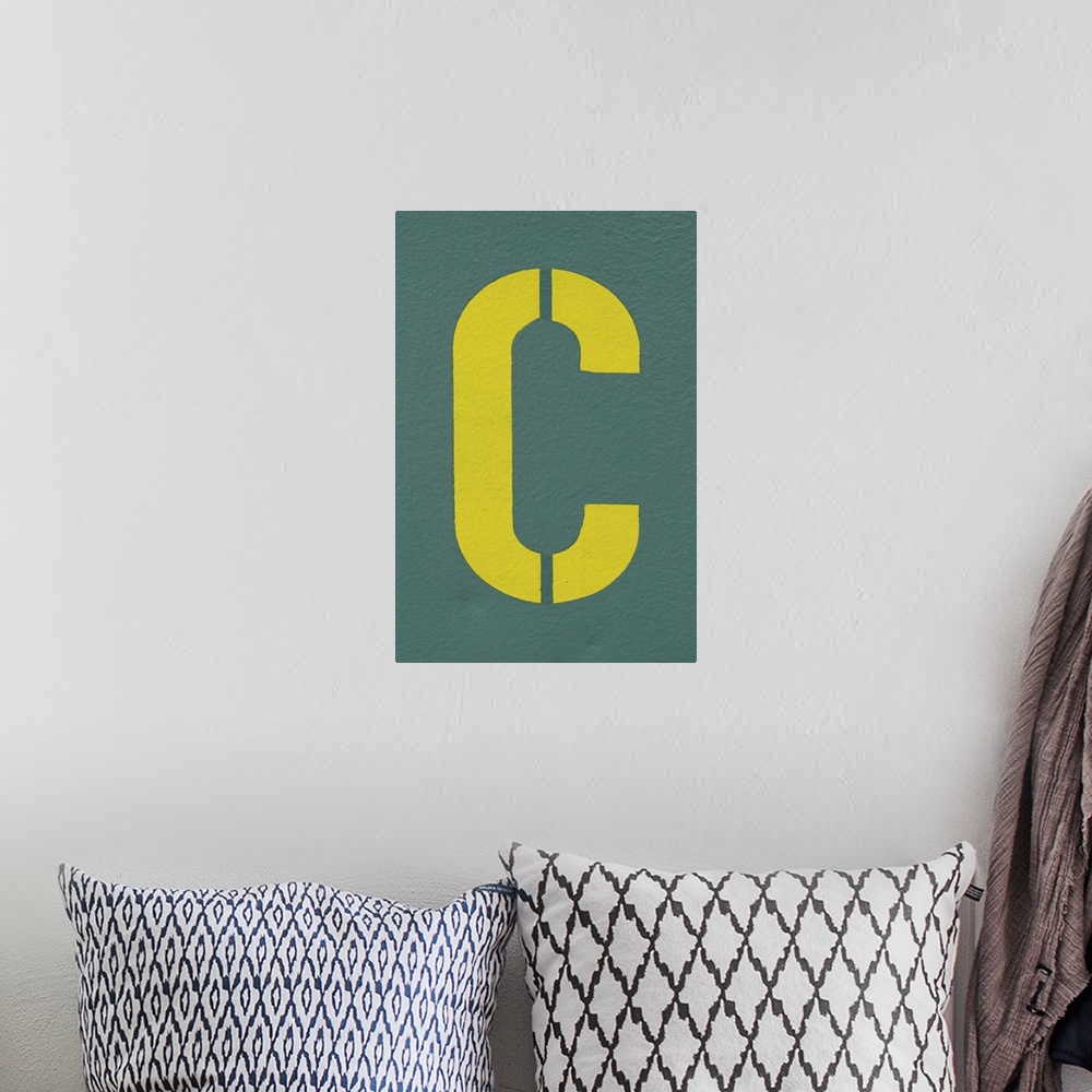 A bohemian room featuring Yellow letter C sprayed on a greyish, green wall.