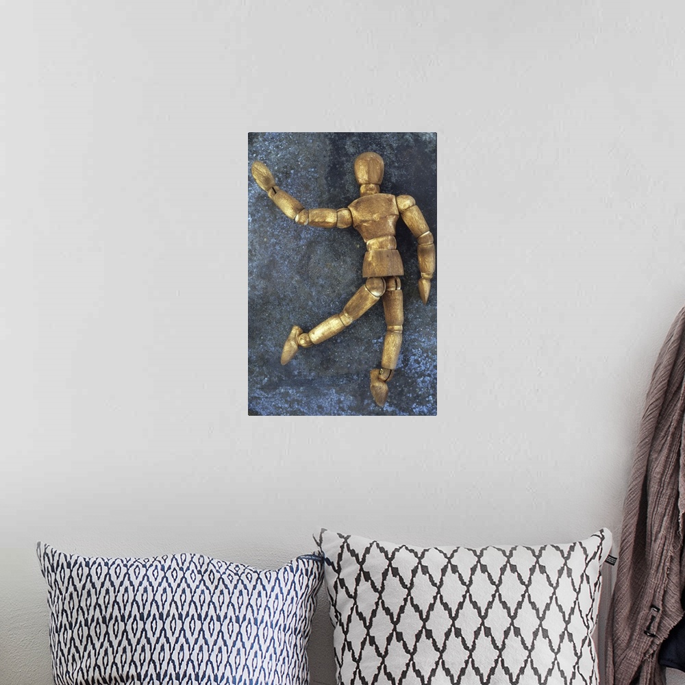 A bohemian room featuring Dark stained wooden mannequin lying on tarnished metal sheet as if running skipping dancing or wa...