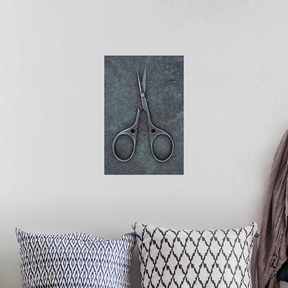 A bohemian room featuring Antique steel sewing scissors decorated with small pattern lying on tarnished metal