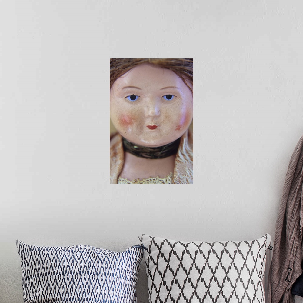A bohemian room featuring Face of vintage woman doll with tight bun and glum face and wearing lacy clothes and neckband