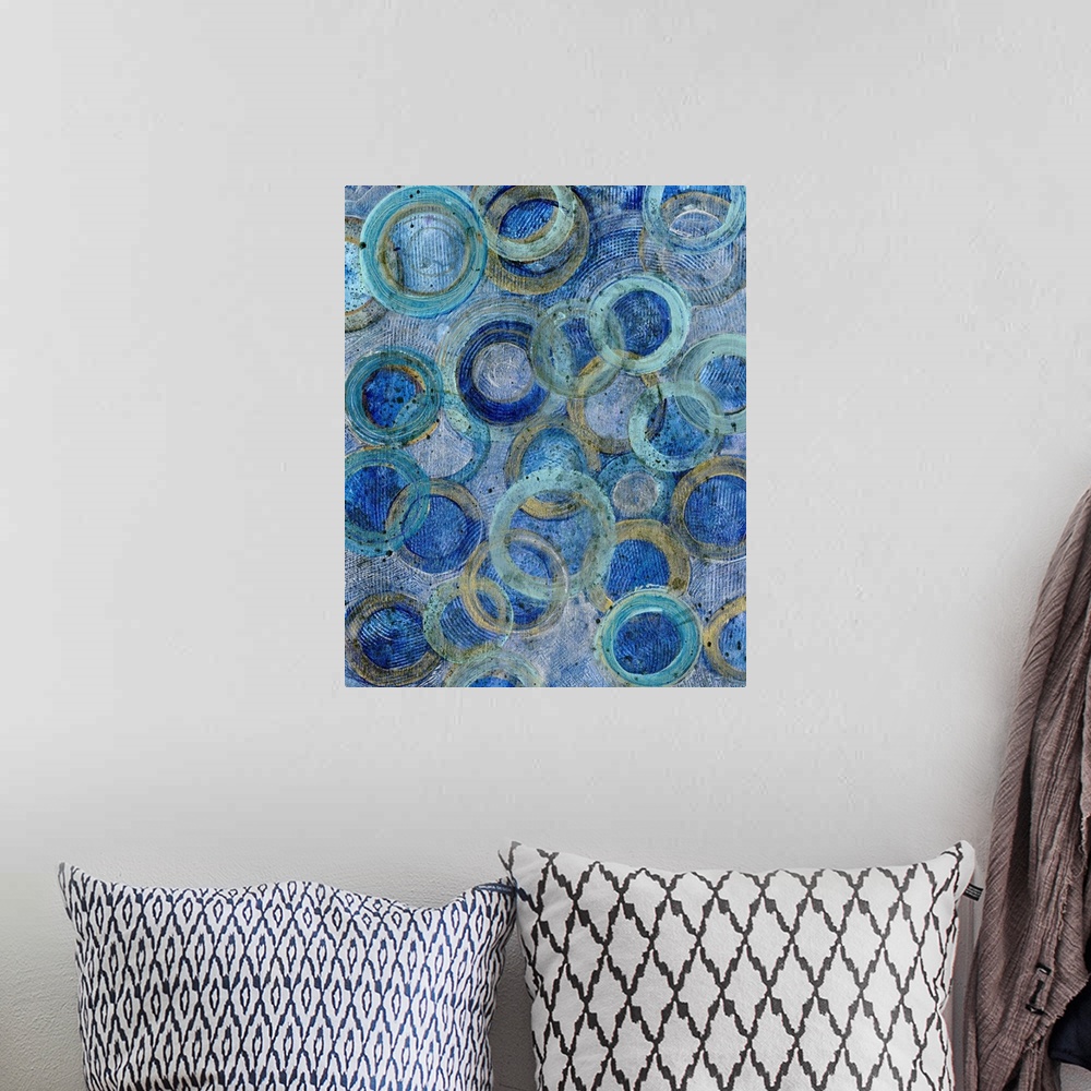 A bohemian room featuring Contemporary abstract artwork of several overlapping rings in blue and gold tones.