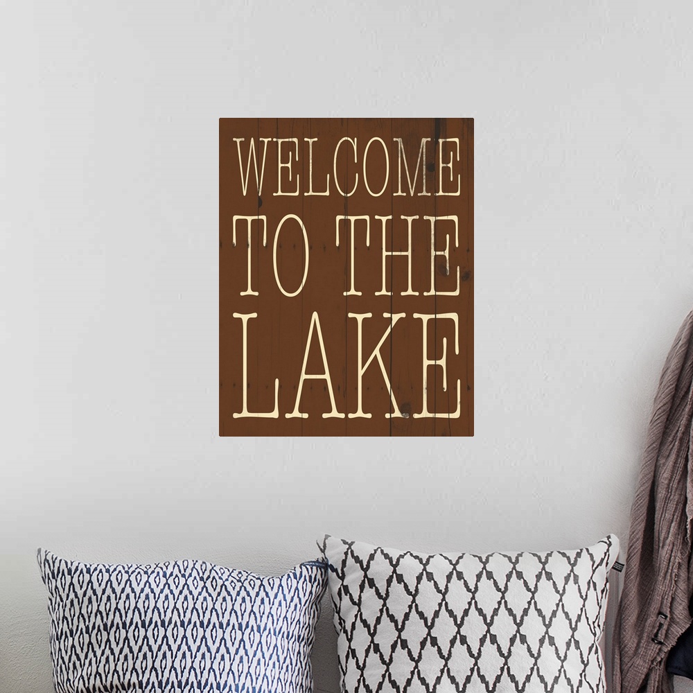 A bohemian room featuring Typographical artwork with "Welcome to the lake" in a thin rustic text.