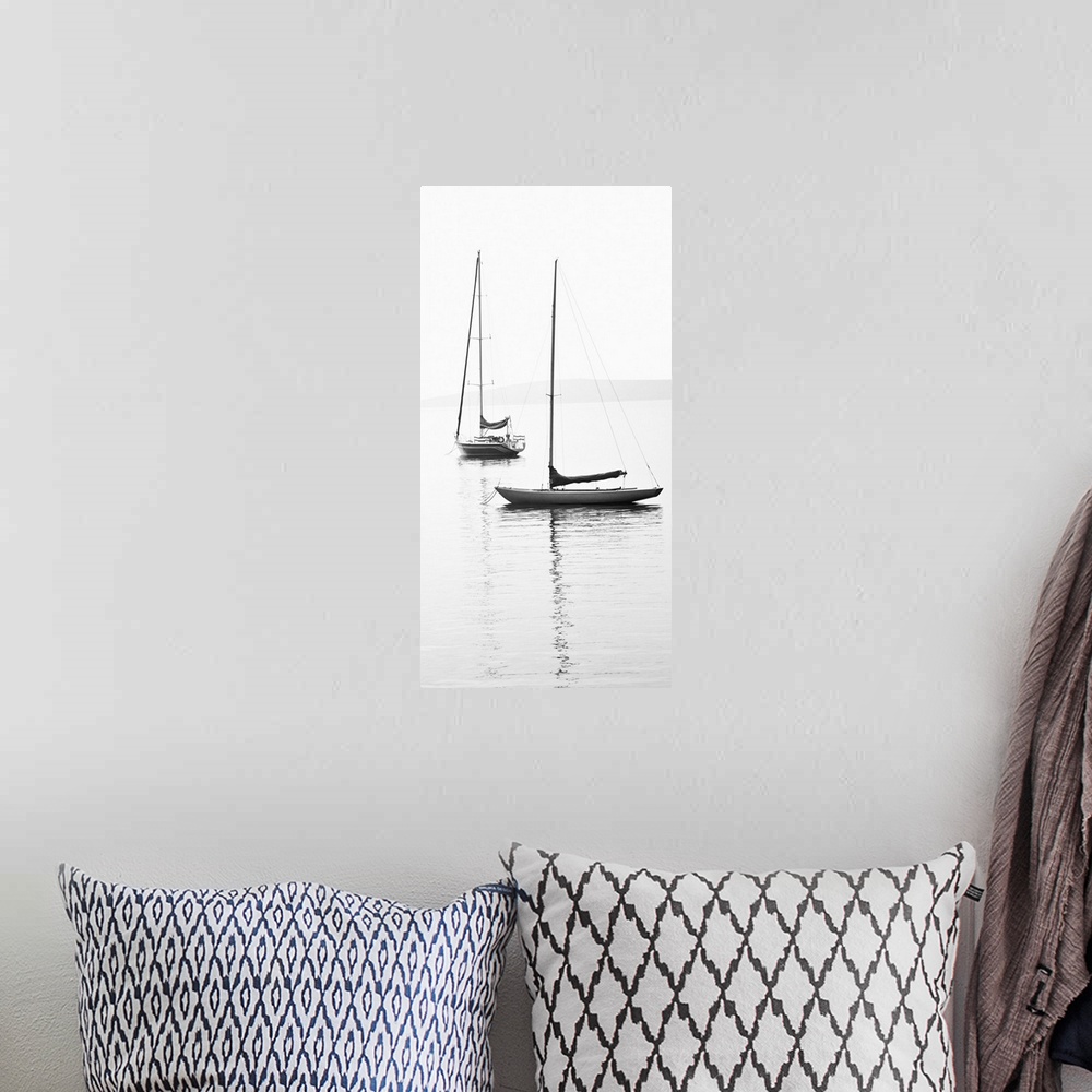 A bohemian room featuring Black and white photograph of two sailboats with sails down on calm water.