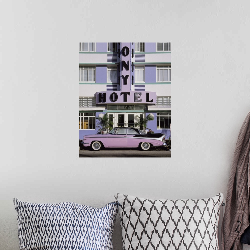 A bohemian room featuring Vertical photograph on a large wall hanging of an old, classic car parked beneath the sign for th...