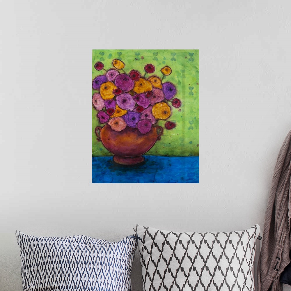 A bohemian room featuring A painting of a red vase holding a bouquet of purple and yellow flowers.