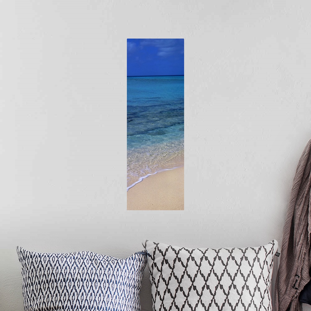 A bohemian room featuring Vertical panorama piece of the crystal clear ocean that is calm as it washes up on the sand.