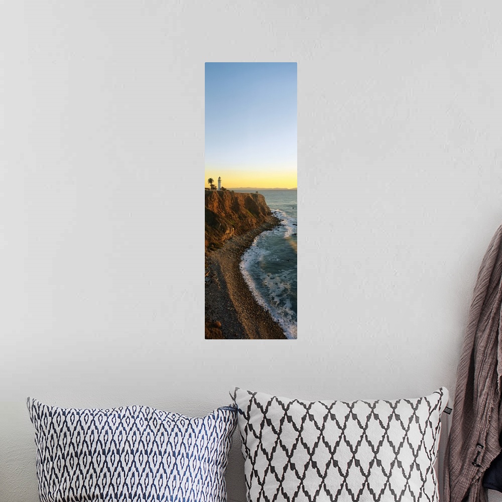 A bohemian room featuring Vertical panoramic canvas of a lighthouse sitting on a cliff near the ocean at sunset.