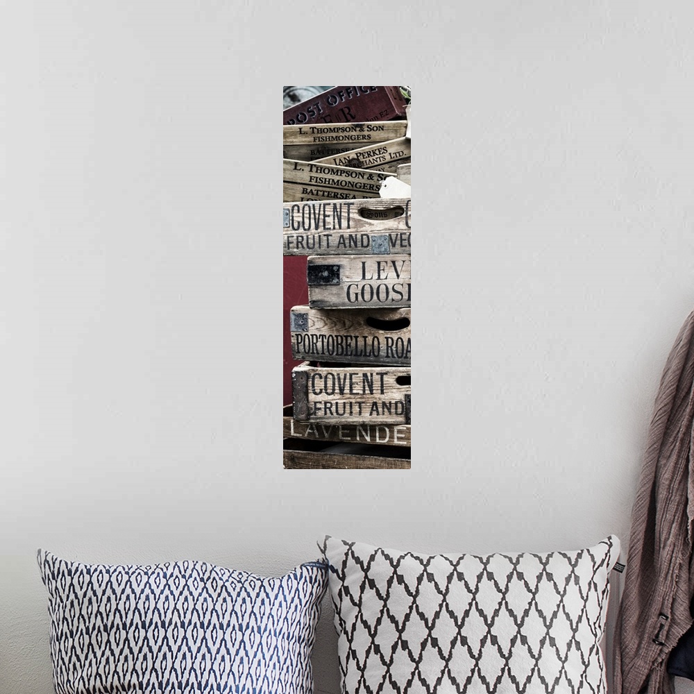 A bohemian room featuring A stack of weathered wooden crates with names of markets lettered on the sides.