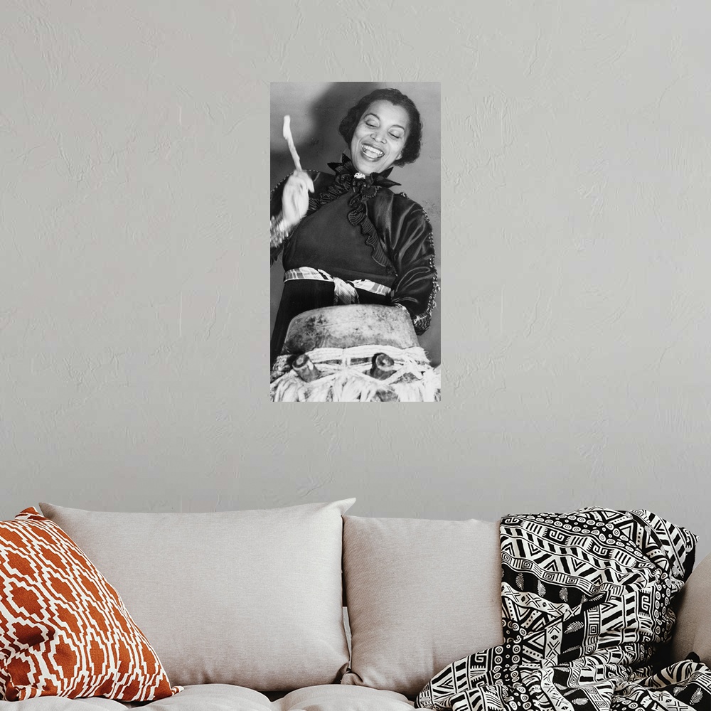 A bohemian room featuring Zora Hurston beating the hountar, or mama drum. 1937 (photo) by American Photographer, (20th cent...