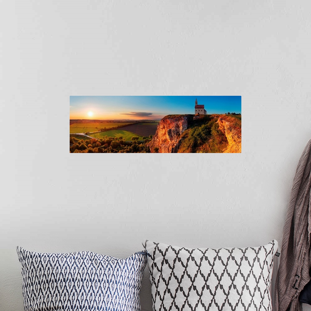 A bohemian room featuring Panoramic image of a church on a cliff overlooking a village in Slovakia at sunset.