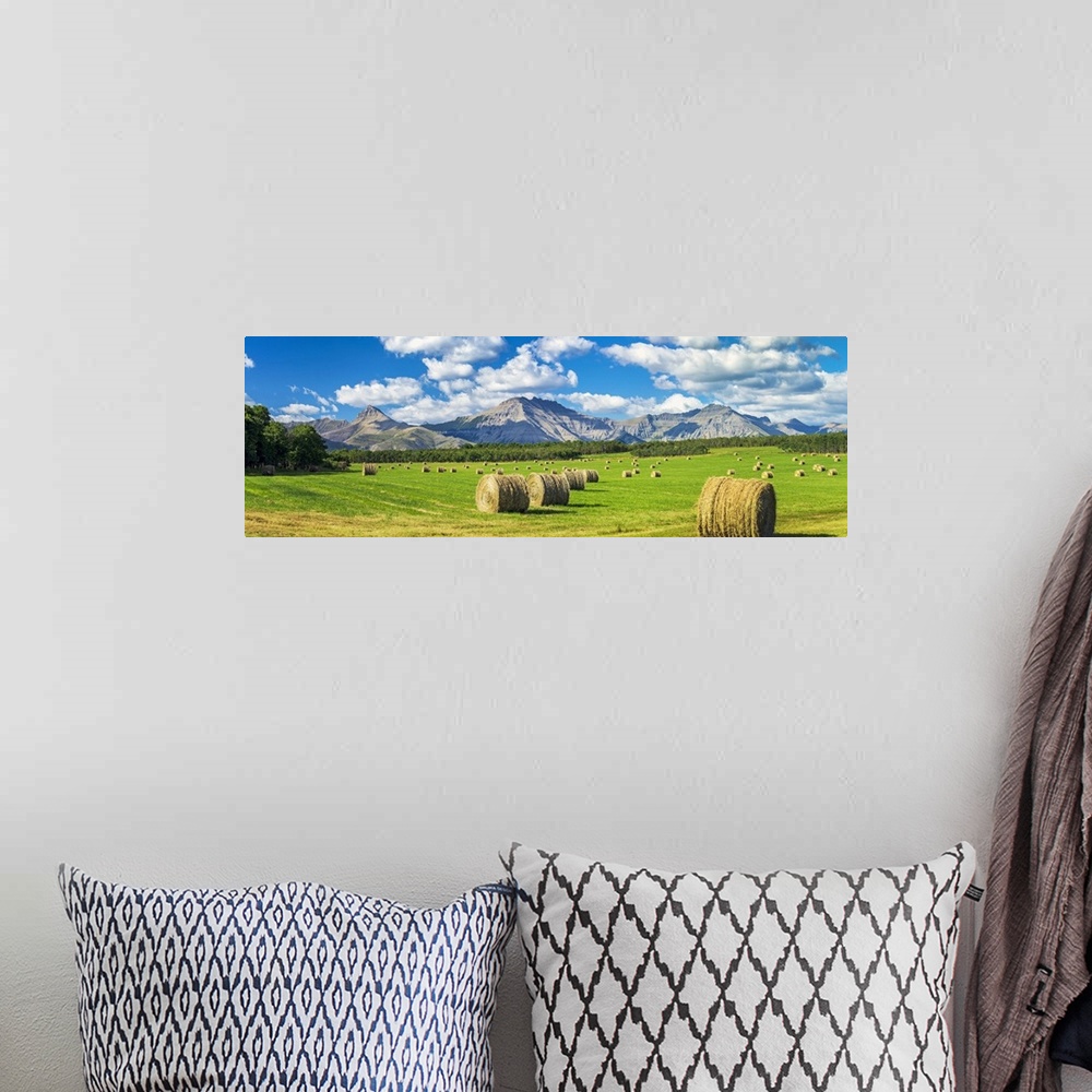A bohemian room featuring Panorama of hay bales in a green field with mountains, blue sky and clouds in the background, Nor...
