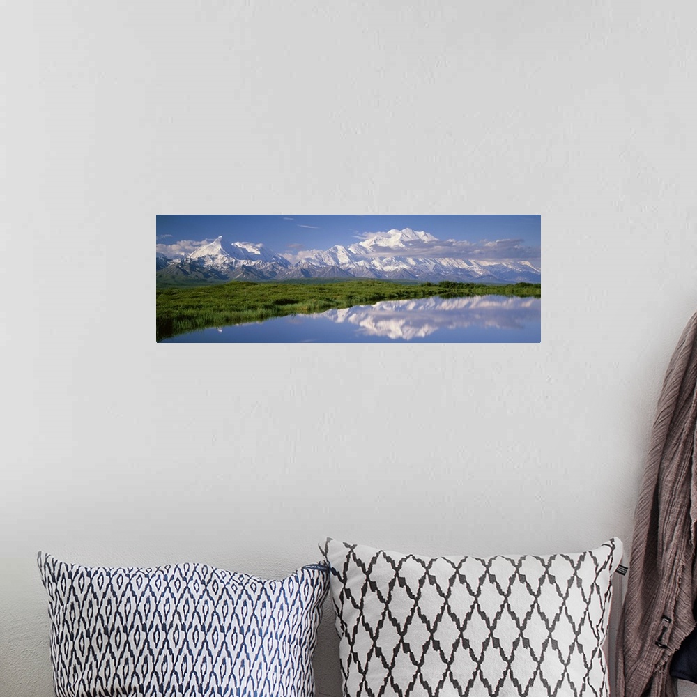 A bohemian room featuring A snow covered mountain range is photographed in panoramic view with a large field shown just in ...